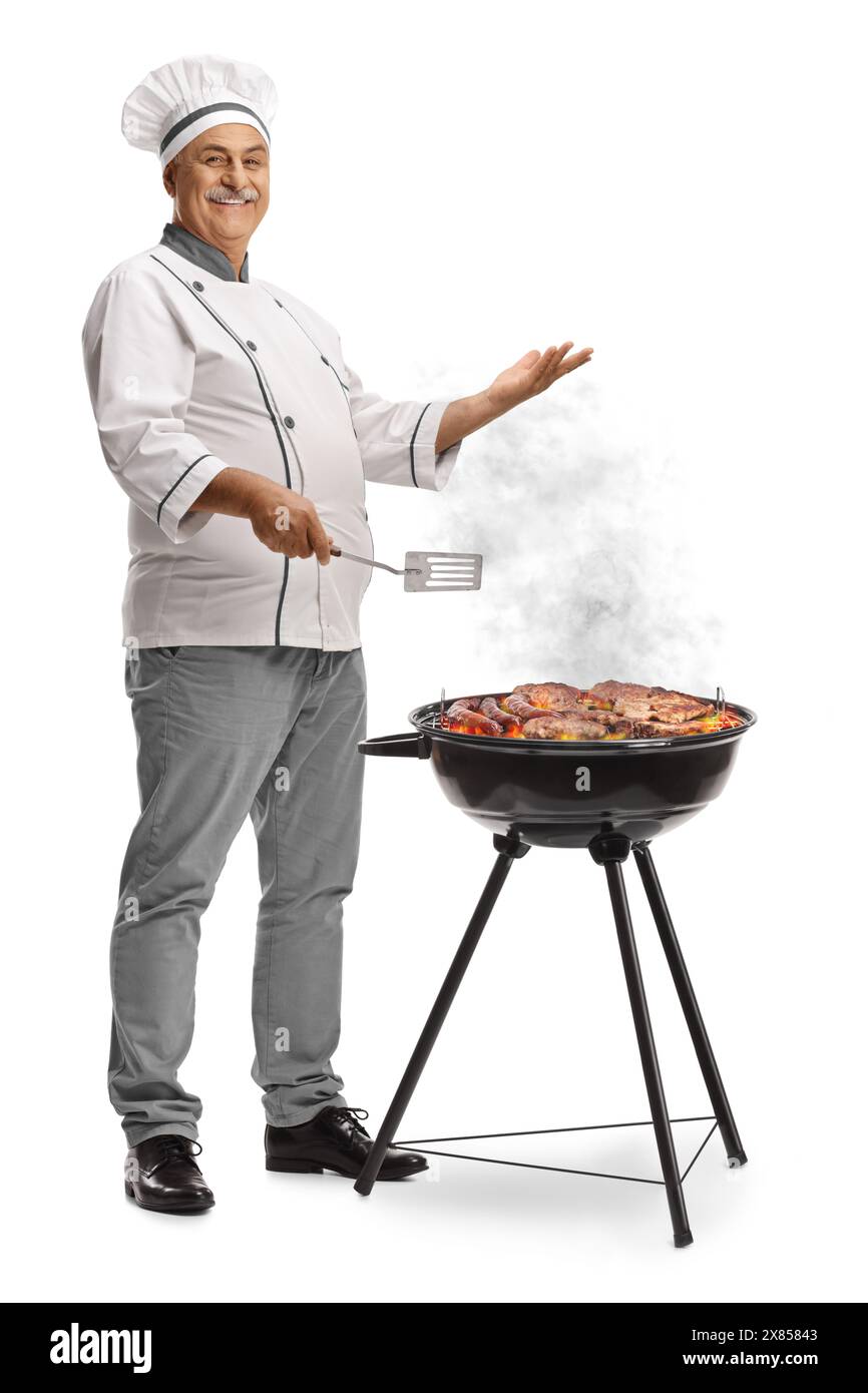 Chef maturo che grigia la carne su un barbecue isolato su sfondo bianco Foto Stock