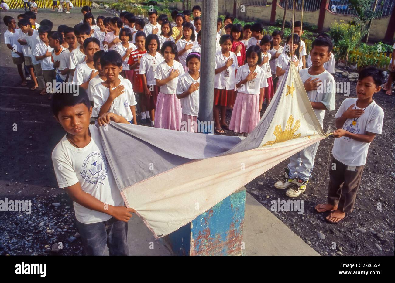 Filippine, Mindanao; i bambini di una scuola elementare alzano la bandiera nazionale e cantano l'inno nazionale al mattino. Foto Stock