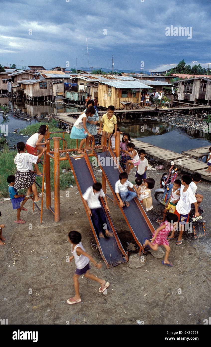 Filippine, Mindanao, bambini scivolati in un quartiere urbano allagato a Davao. Foto Stock