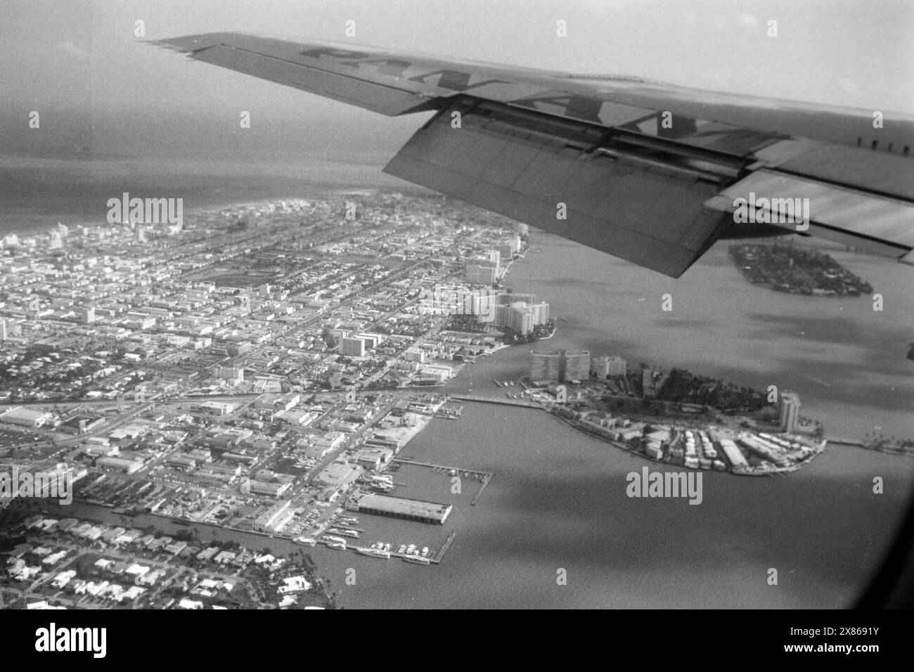 Blick über die Biscayne Bay aus dem Fenster einer Pan Am Machine, Links Die Landzunge von Miami Beach mit Verbindungsstraße zu der Insel Belle Isle, einer der sechs künstlichen Inseln der Gruppe Venetian Islands und der ebenfalls künstlichen Insel Star Island im Hintergrund, Florida 1966. Ammira la baia di Biscayne dalla finestra di una Pan Am Machine, sulla sinistra il promontorio di Miami Beach con la strada di collegamento per Belle Isle, una delle sei isole artificiali del gruppo delle Venetian Islands e l'anche artificiale Star Island sullo sfondo, Florida 1966. Foto Stock