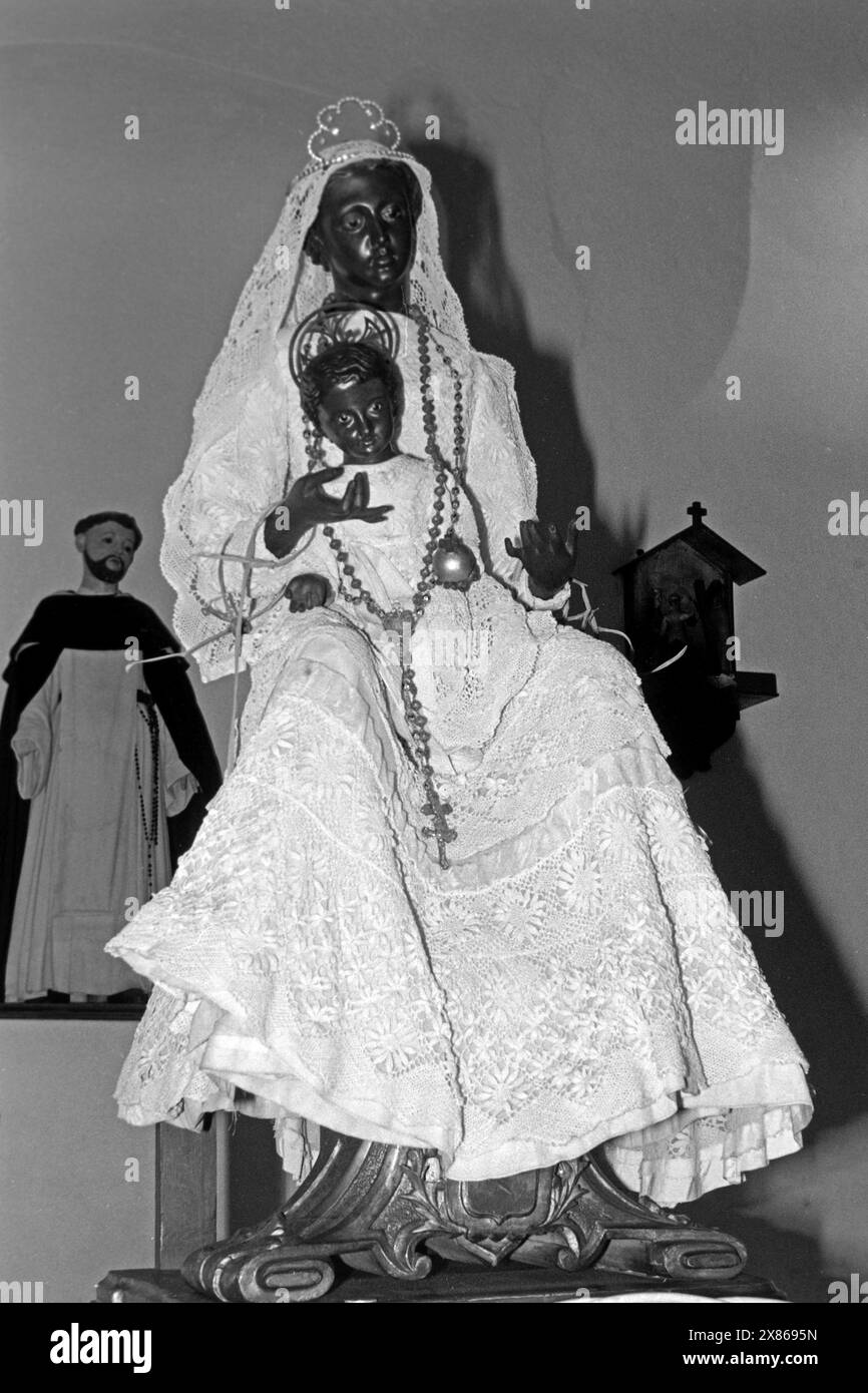 Die Figur einer Schwarzen Madonna mit Kind, im Hintergrund eine Figur des Heiligen Franz von Assisi nel dem Museum porta Coeli a San Germán, Porto Rico 1966. La figura di una Madonna Nera con bambino, sullo sfondo una figura di San Francesco d'Assisi nel Museo porta Coeli di San Germán, Porto Rico 1966. Foto Stock