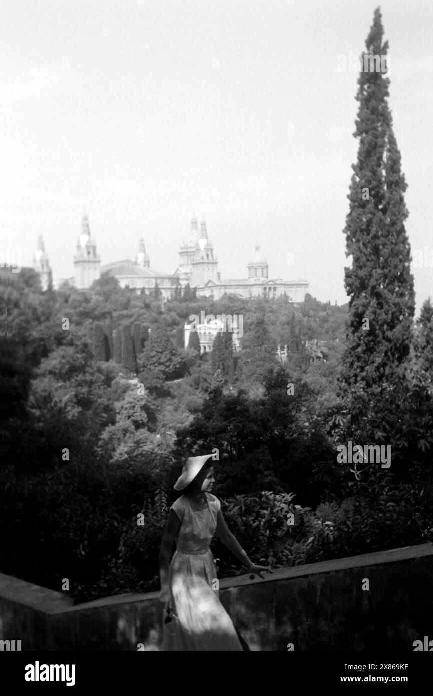 Eine junge Frau erklimmt eine Treppe, im Hintergrund ist der Palau Nacional von Barcelona erkennbar, 1957.Una giovane donna sale una scala, il Palau Nacional di Barcellona è riconoscibile sullo sfondo, 1957. Foto Stock