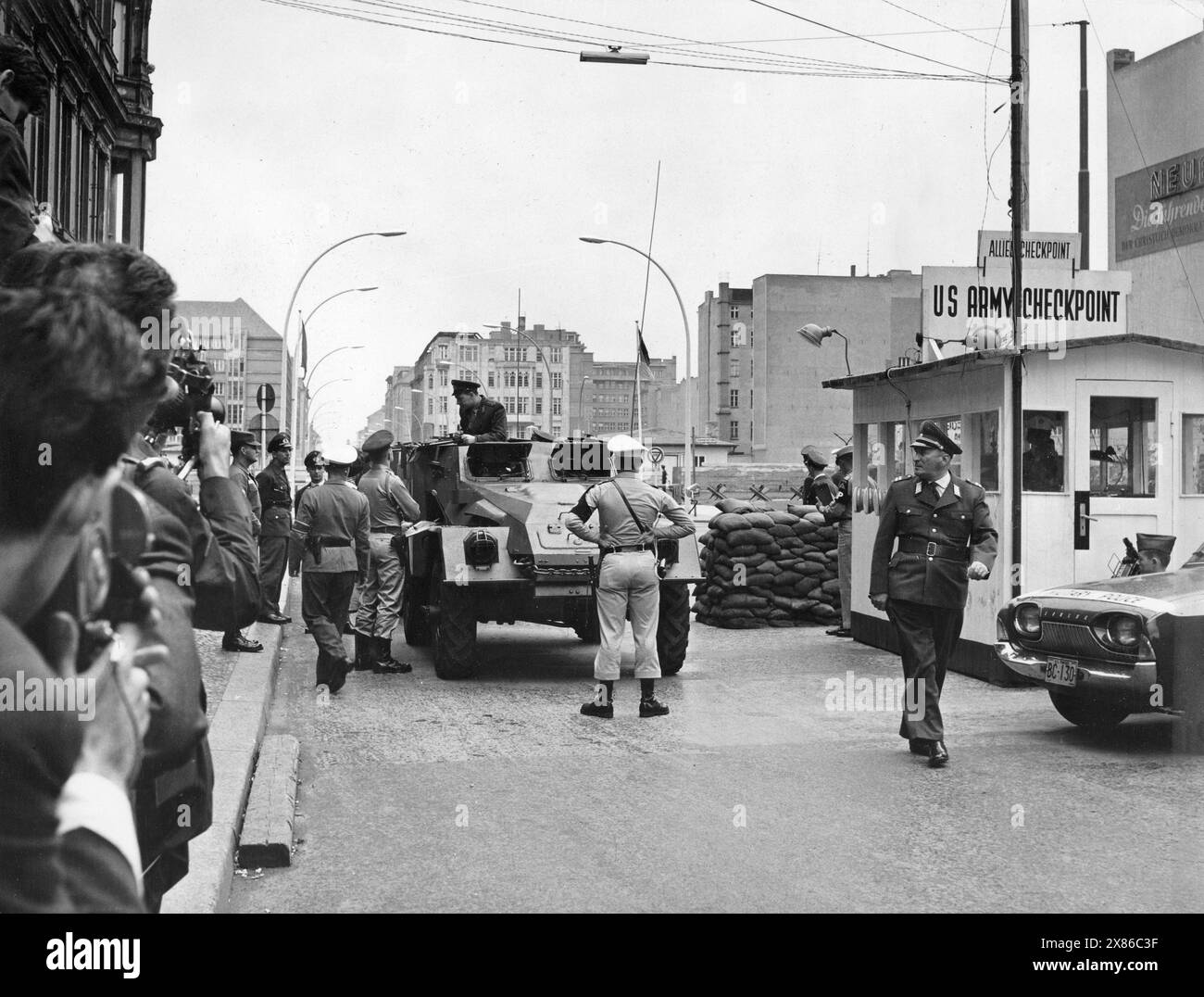Ein US-Soldat macht sich demonstrativ vor einem sowjetischen Schützenpanzer breit, während dieser am Checkpoint Charlie durchsucht wird, Berlino 1962. - Originale Bildbeschreibung: 'Wachablösung der Sowjets im Westsektor' - Auch heute, um 14,30 Uhr, fuhren die Sowjets mit ihren drei Schützenpanzerwagen durch den Kontrollpunkt an der Friedrichstrasse. SIE wurden von amerikanischen Fahrzeugen sowie der Berliner Polizei eskortiert. - U.B.z.: AM Kontrollpunkt 'Checkpoint Charlie'' Foto Stock