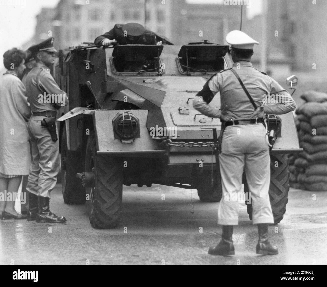Ein US-Soldat macht sich demonstrativ vor einem sowjetischen Schützenpanzer breit, während dieser am Checkpoint Charlie durchsucht wird, Berlino 1962. - Originale Bildbeschreibung: 'Besichtigungsfahrt der Sowjets im Westsektor' - Auch heute, um 14,30 Uhr, fuhren die Sowjets mit ihren drei Schützenpanzerwagen durch den Kontrollpunkt an der Friedrichstrasse. SIE wurden von amerikanischen Fahrzeugen sowie der Berliner Polizei eskortiert. - U.B.z.: AM Kontrollpunkt 'Checkpoint Charlie'' Foto Stock