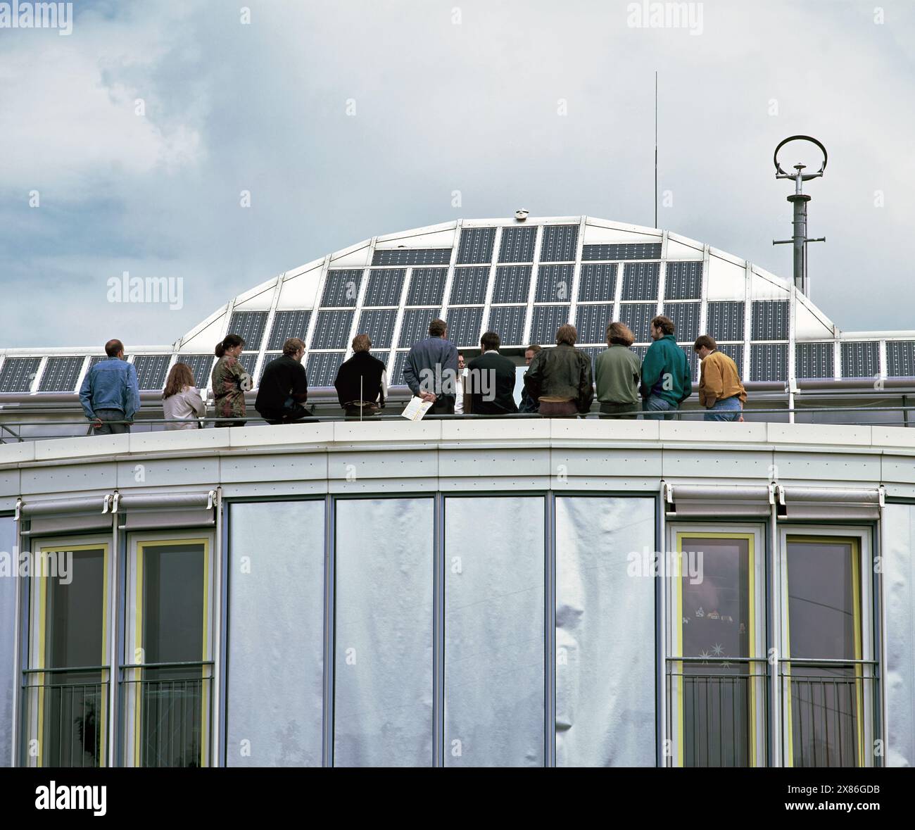 Visitatori che ammirano una serie di celle fotovoltaiche sul tetto della Self Enough Solar House, Friburgo in Brisgovia, Germania. Foto Stock