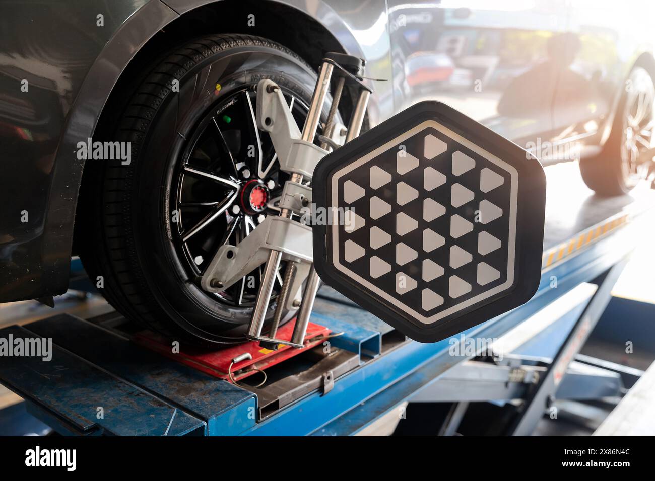 Calibrare l'equilibratrice delle ruote per auto con riflettore laser fissare su ogni pneumatico per centrare la regolazione di guida. Auto in servizio. Macchina con ruote per equilibratura. Foto Stock