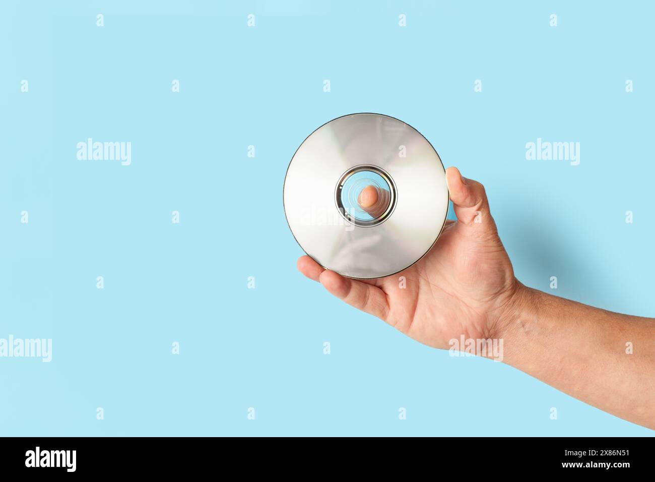 Uomo che tiene a mano un CD su sfondo blu con spazio di copia Foto Stock