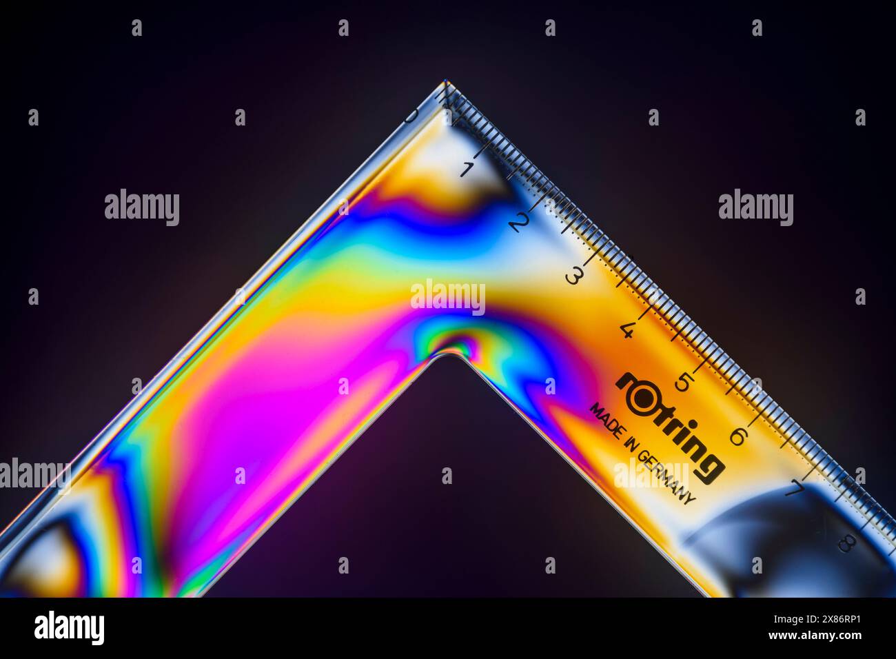 Dettaglio da un set triangolare di 90/45 gradi in plastica trasparente Rotring visto tra i filtri di polarizzazione incrociati. Foto Stock