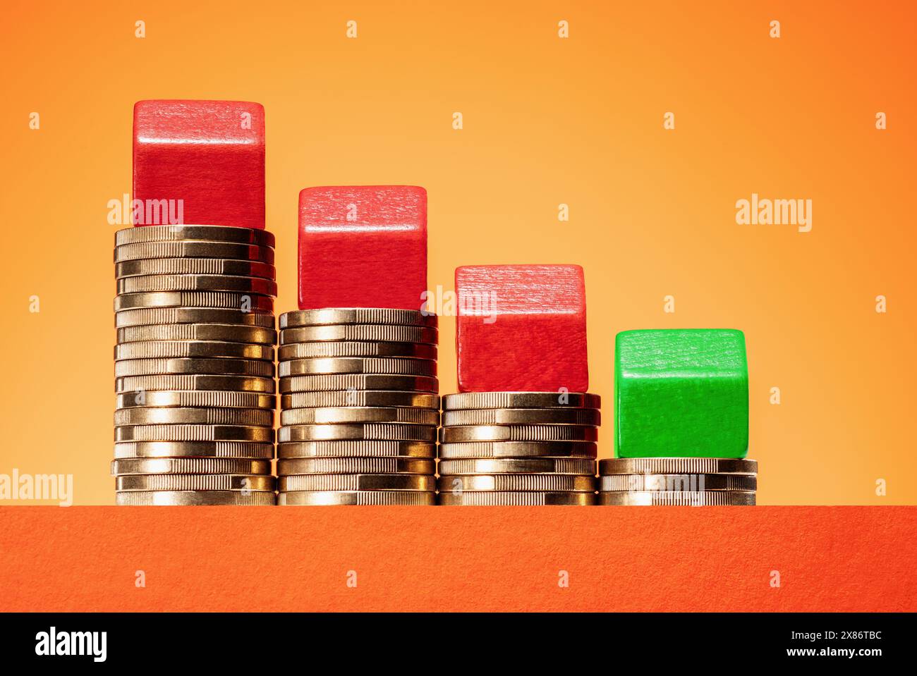 Concetto di calo dei prezzi immobiliari. Case su pile di soldi in pendenza. Foto Stock