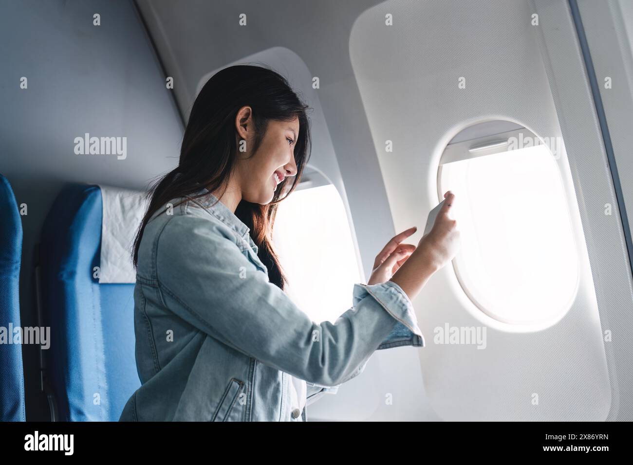 Viaggiatore hipster che scatta foto della finestra durante le vacanze estive su un aereo passeggeri. Concetto di catturare momenti durante il volo Foto Stock