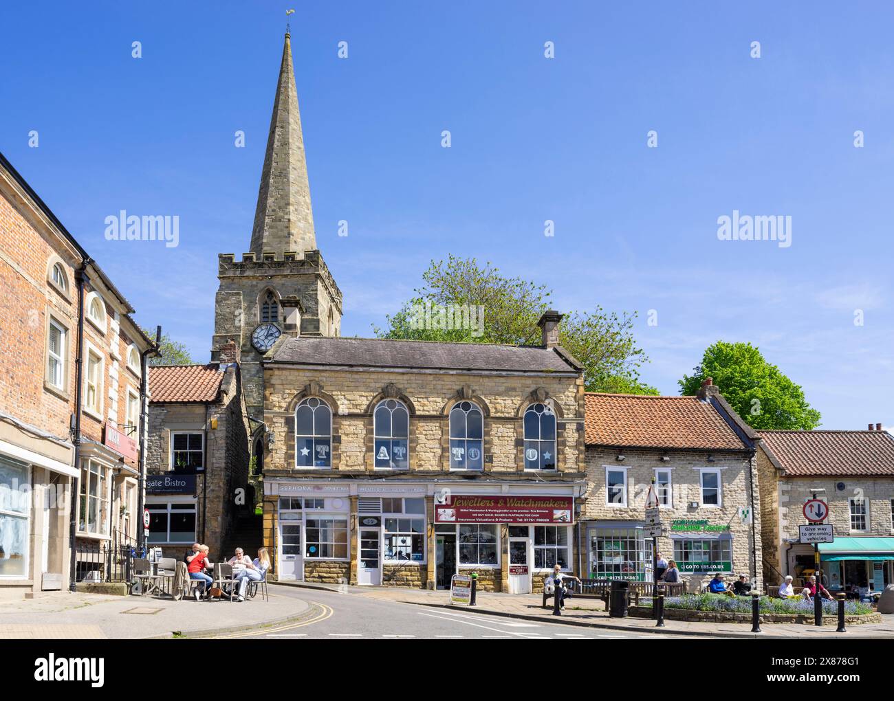 Pickering Shops on the Market Place and Birdgate con la torre di St Peter and St Paul's Church Pickering North Yorkshire Inghilterra Regno Unito Europa Foto Stock