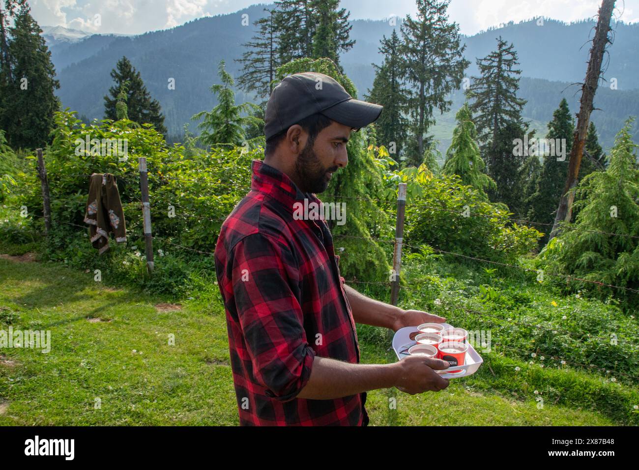 Un uomo del Kashmir serve Noon Chai (tè salato) ai turisti e alla gente del posto passando per la sua bancarella lungo la strada Doodhpathri nel distretto di Budgam, a sud-ovest di Srinagar. Le autorità hanno chiesto ai proprietari dei venditori di tè di liberare lo spazio che hanno occupato "illegalmente" entro dieci giorni o di affrontare azioni. I funzionari hanno detto a un'agenzia di stampa locale che l'autorità per lo sviluppo del turismo ha ricevuto molte lamentele per il fatto che i proprietari delle bancarelle di tè hanno tagliato rami di alberi, danneggiando così i pittoreschi prati. Sulla strada per i prati della famosa località turistica di Doodhpathri, la zona si trova a Foto Stock