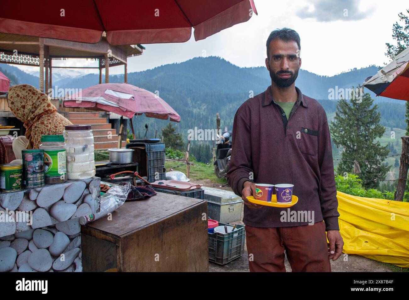 Un uomo del Kashmir serve Noon Chai (tè salato) ai turisti e alla gente del posto passando per la sua bancarella lungo la strada Doodhpathri nel distretto di Budgam, a sud-ovest di Srinagar. Le autorità hanno chiesto ai proprietari dei venditori di tè di liberare lo spazio che hanno occupato "illegalmente" entro dieci giorni o di affrontare azioni. I funzionari hanno detto a un'agenzia di stampa locale che l'autorità per lo sviluppo del turismo ha ricevuto molte lamentele per il fatto che i proprietari delle bancarelle di tè hanno tagliato rami di alberi, danneggiando così i pittoreschi prati. Sulla strada per i prati della famosa località turistica di Doodhpathri, la zona si trova a Foto Stock