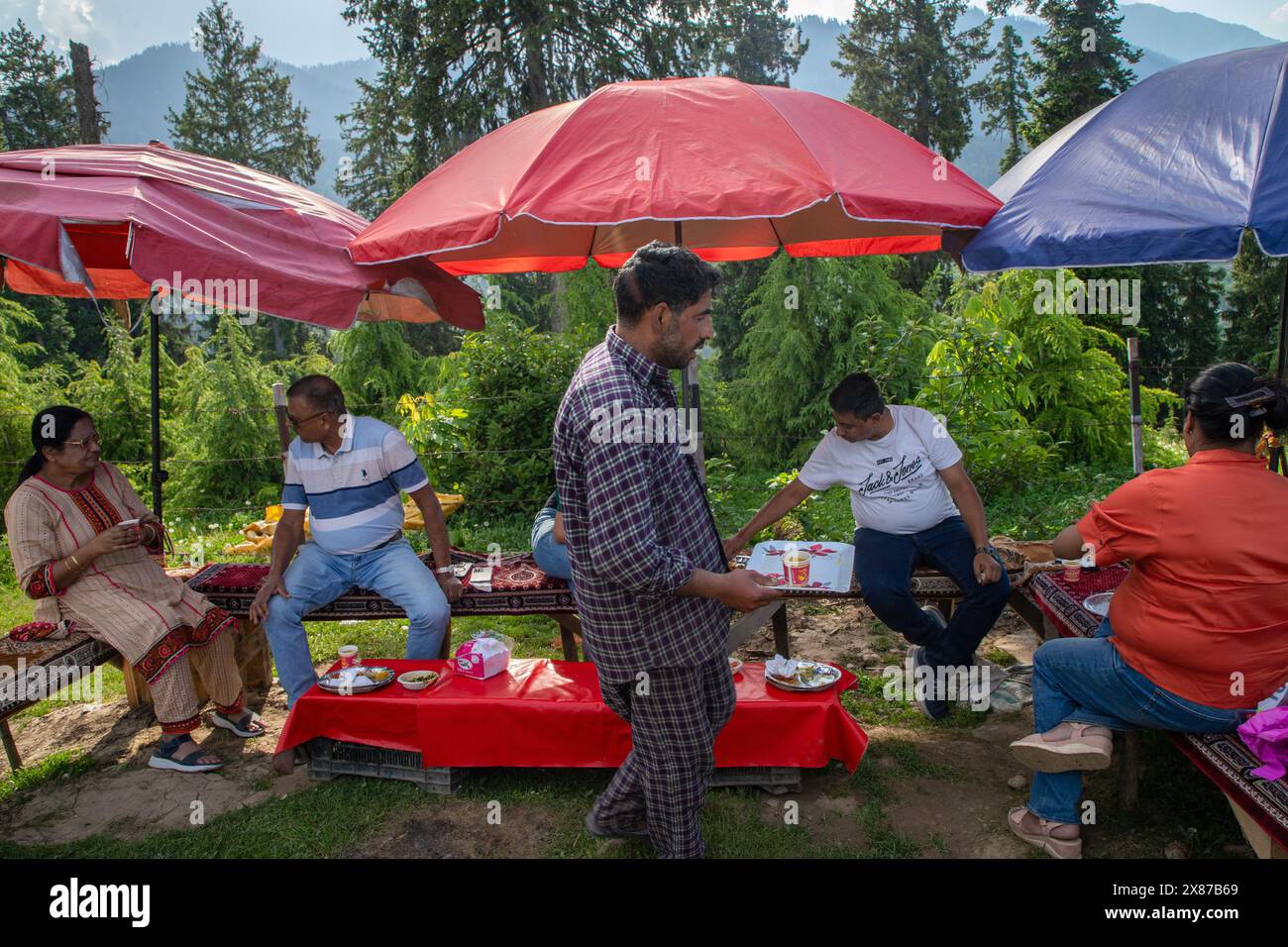 Un uomo del Kashmir serve Noon Chai (tè salato) ai turisti e alla gente del posto passando per la sua bancarella lungo la strada Doodhpathri nel distretto di Budgam, a sud-ovest di Srinagar. Le autorità hanno chiesto ai proprietari dei venditori di tè di liberare lo spazio che hanno occupato "illegalmente" entro dieci giorni o di affrontare azioni. I funzionari hanno detto a un'agenzia di stampa locale che l'autorità per lo sviluppo del turismo ha ricevuto molte lamentele per il fatto che i proprietari delle bancarelle di tè hanno tagliato rami di alberi, danneggiando così i pittoreschi prati. Sulla strada per i prati della famosa località turistica di Doodhpathri, la zona si trova a Foto Stock