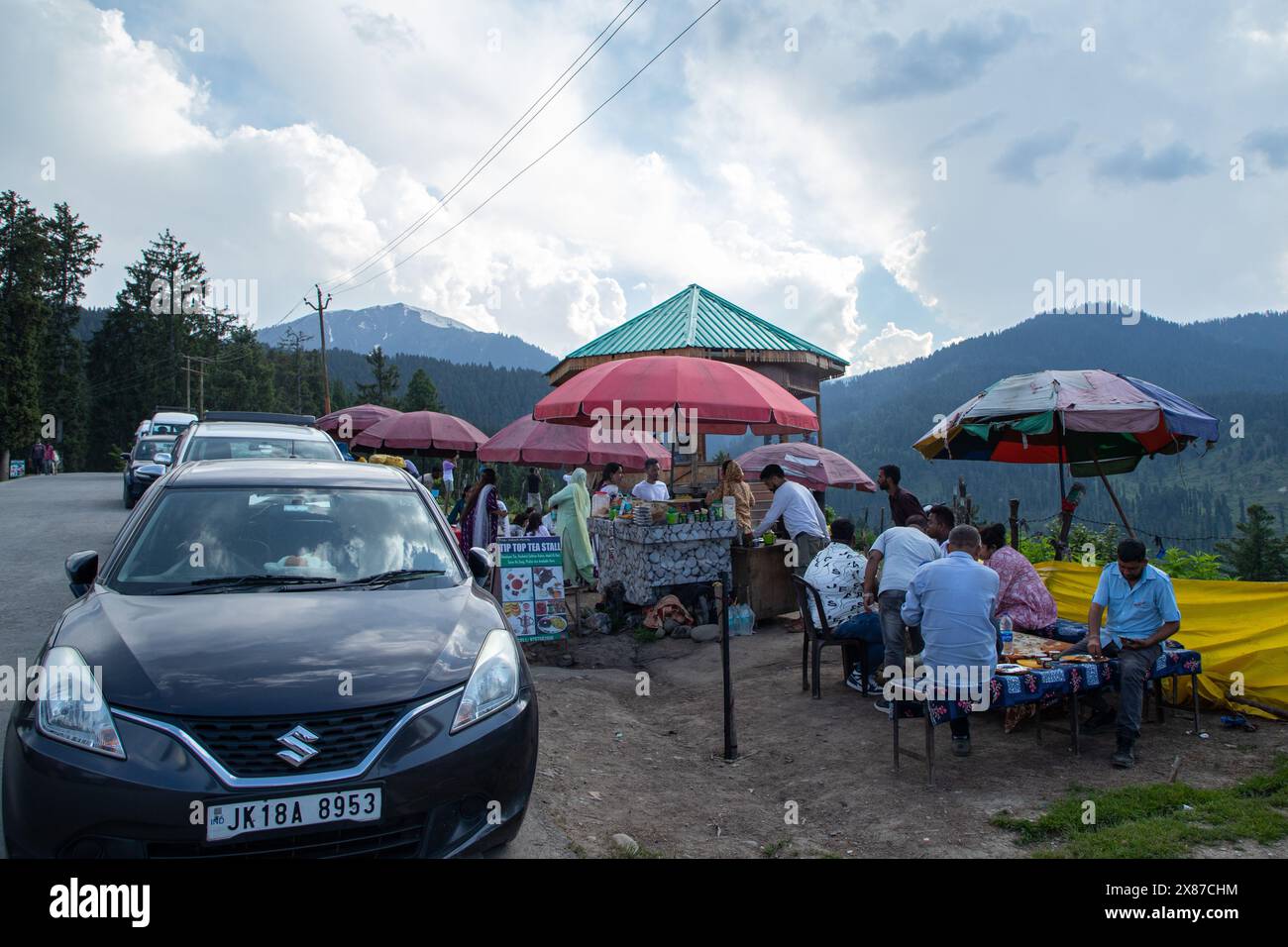 I veicoli sono parcheggiati lungo una strada mentre i turisti e la gente del posto si godono il Noon Chai (tè salato) con tortillas di farina di mais in una stalla lungo la strada Doodhpathri nel quartiere di Budgam, a sud-ovest di Srinagar. Le autorità hanno chiesto ai proprietari dei venditori di tè di liberare lo spazio che hanno occupato "illegalmente" entro dieci giorni o di affrontare azioni. I funzionari hanno detto a un'agenzia di stampa locale che l'autorità per lo sviluppo del turismo ha ricevuto molte lamentele per il fatto che i proprietari delle bancarelle di tè hanno tagliato rami di alberi, danneggiando così i pittoreschi prati. Sulla strada per i prati della famosa t Foto Stock