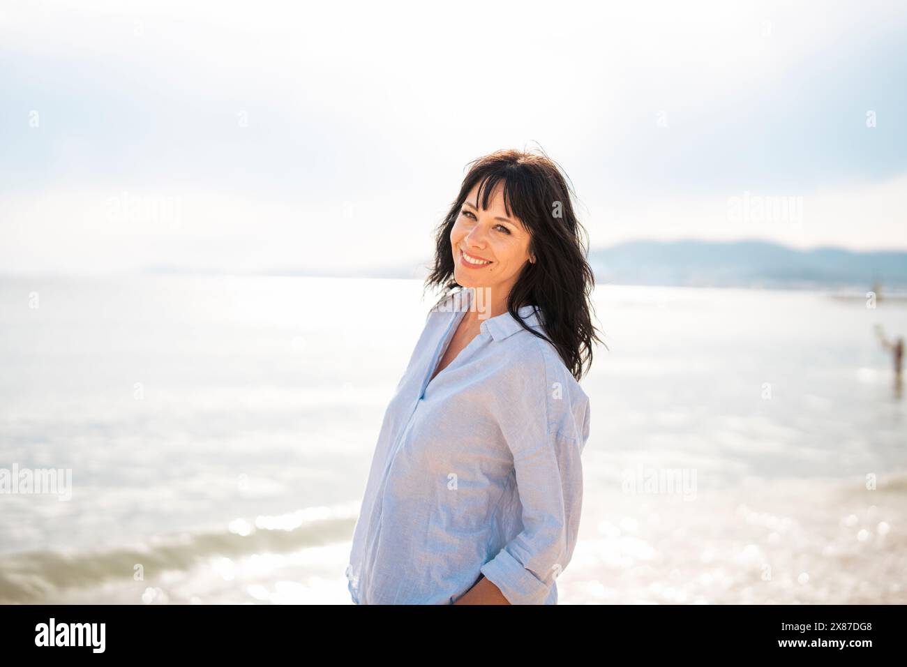 Donna sorridente che trascorre il tempo libero in spiaggia Foto Stock