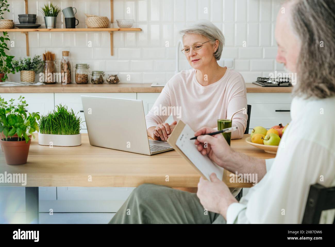 Nutrizionista maturo con il menu planner per il riempimento dei clienti a casa Foto Stock