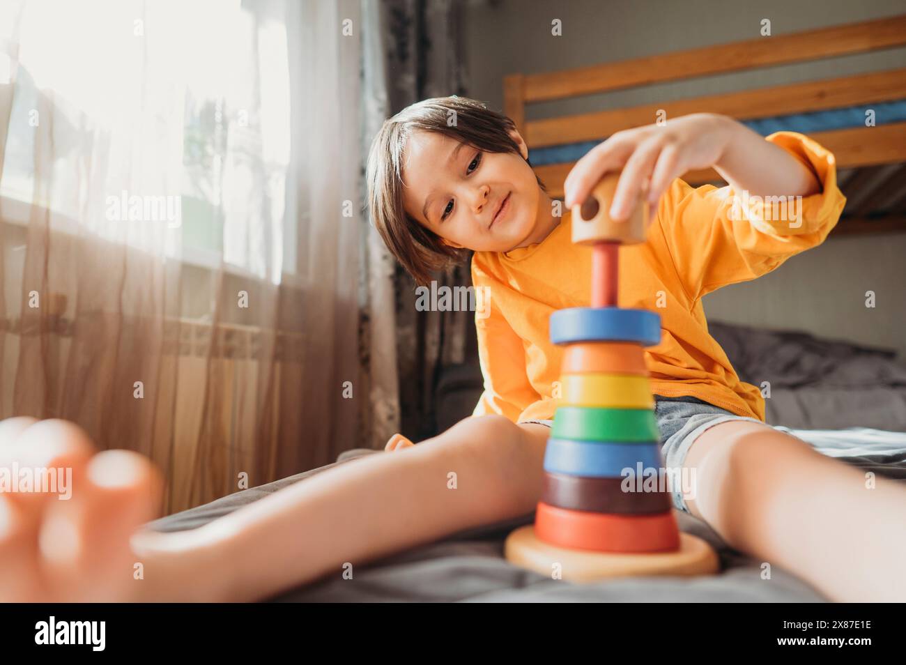 Ragazzo carino che gioca con un gioco educativo a casa Foto Stock