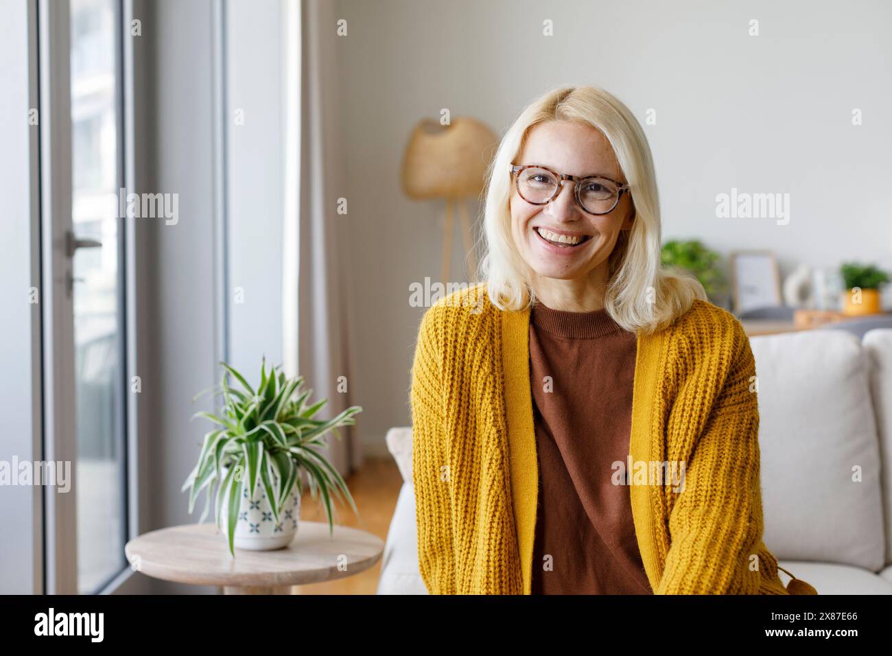Donna matura felice in maglione cardigan a casa Foto Stock