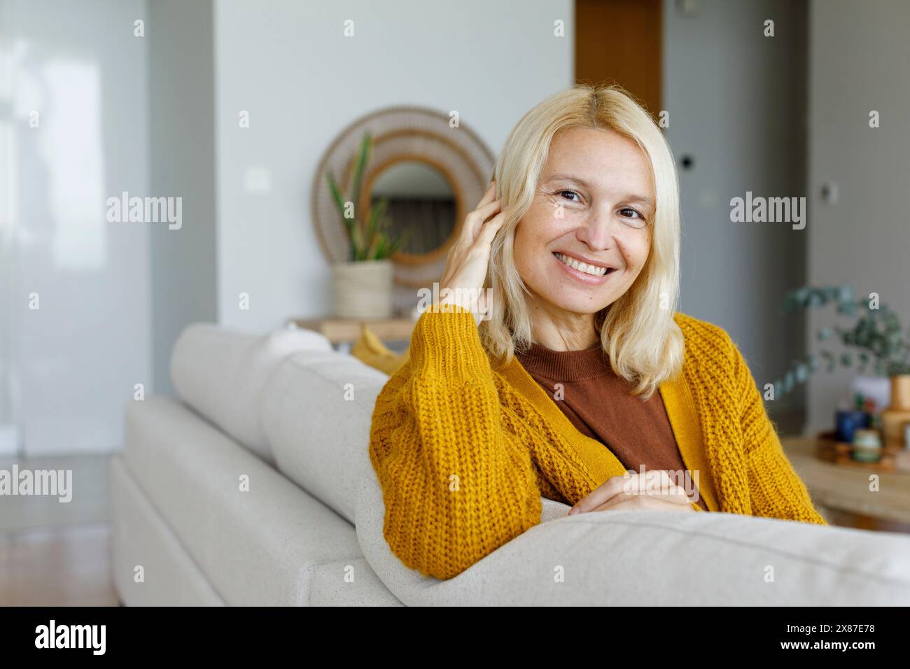 Donna felice in appoggio sul divano di casa Foto Stock