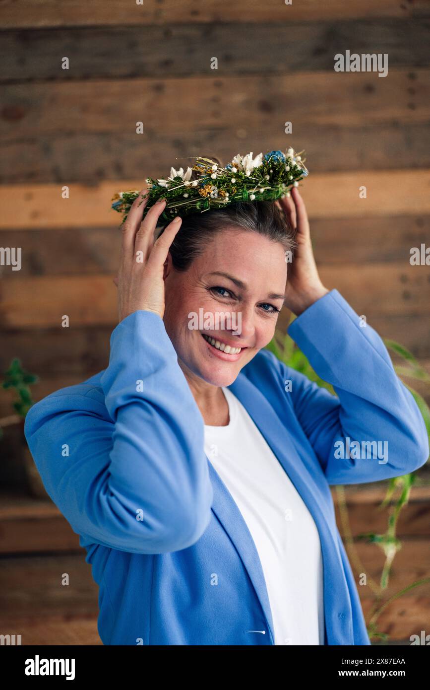 Donna d'affari felice che indossa una corona di fiori Foto Stock