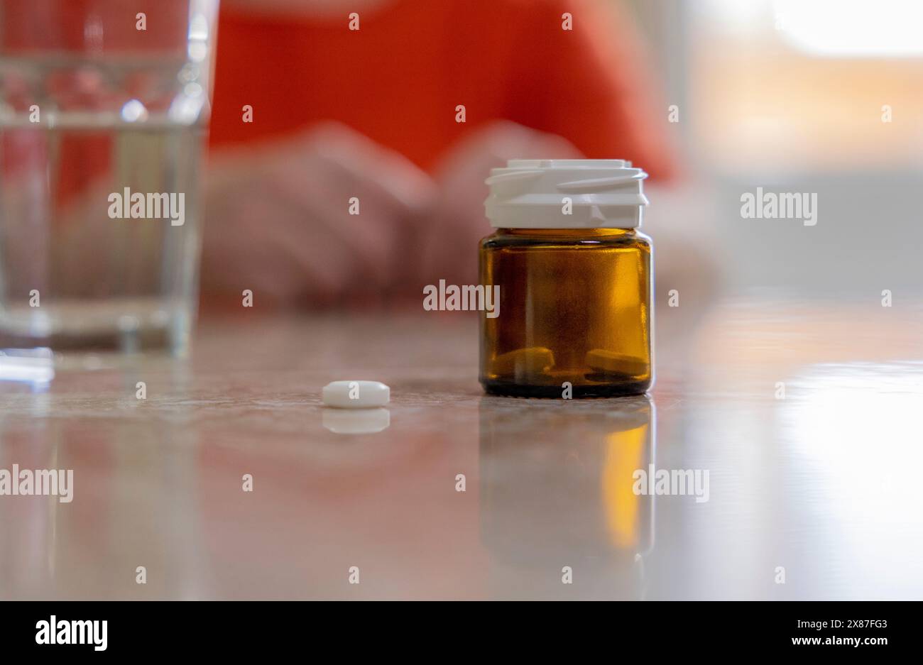 Bottiglia trasparente di pillole sul tavolo a casa Foto Stock