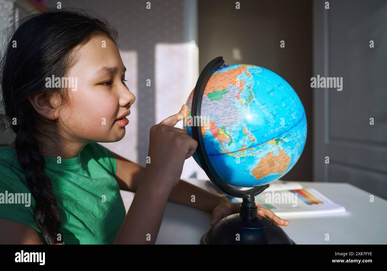Ragazza che impara geografia usando il globo a casa Foto Stock