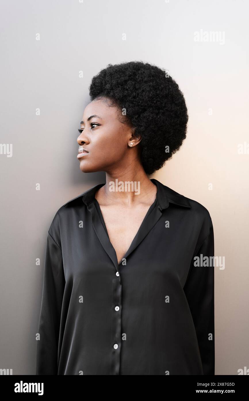 Donna afro premurosa in piedi vicino al muro Foto Stock