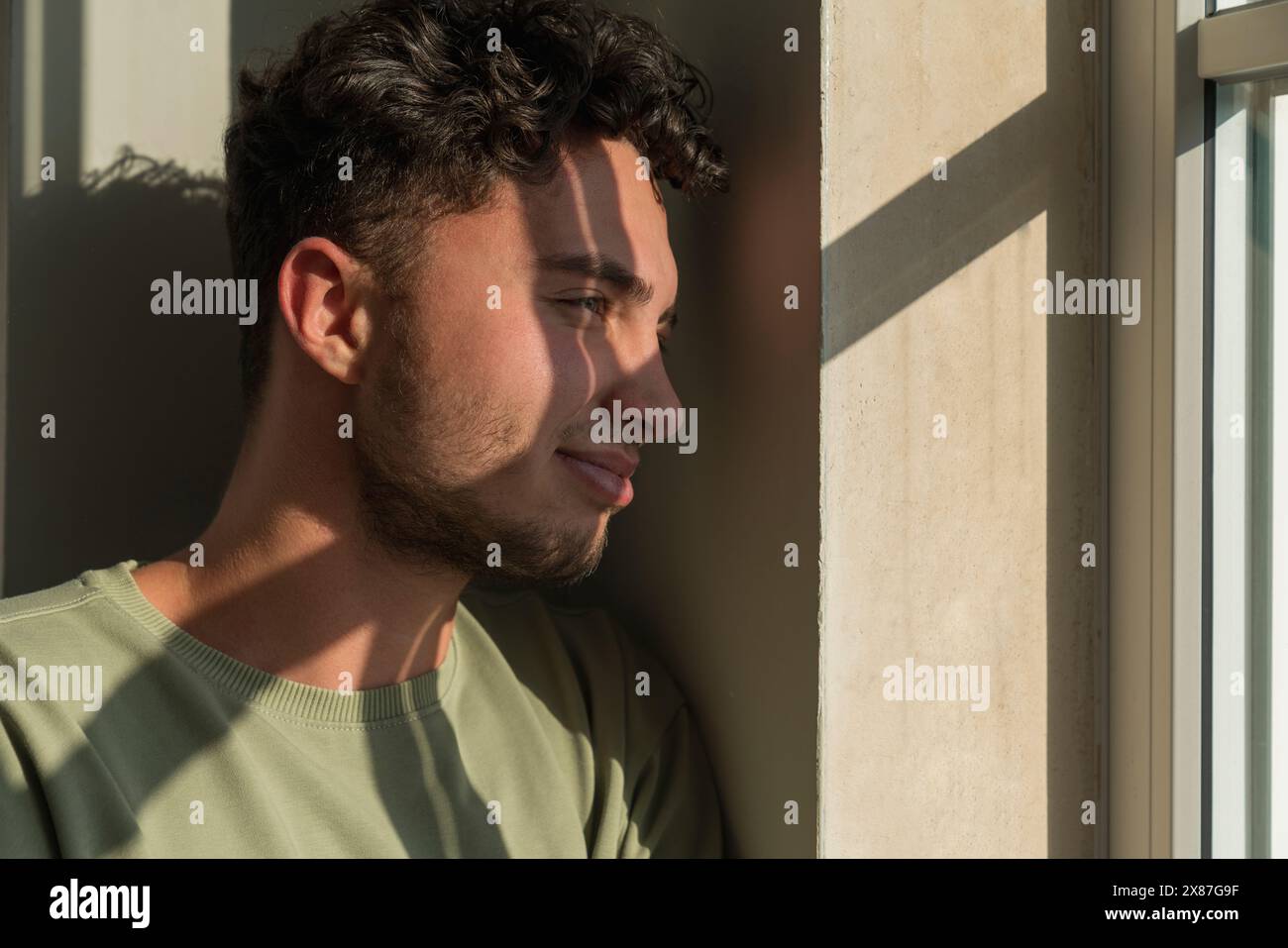 Un giovane premuroso che guarda dalla finestra Foto Stock