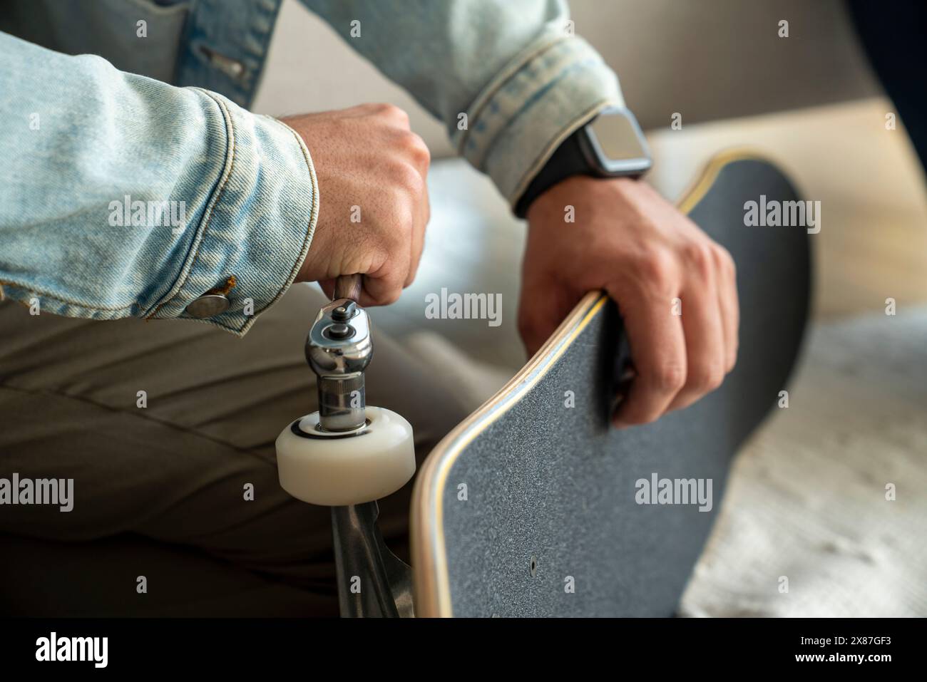 Giovane che ripara la ruota dello skateboard a casa Foto Stock