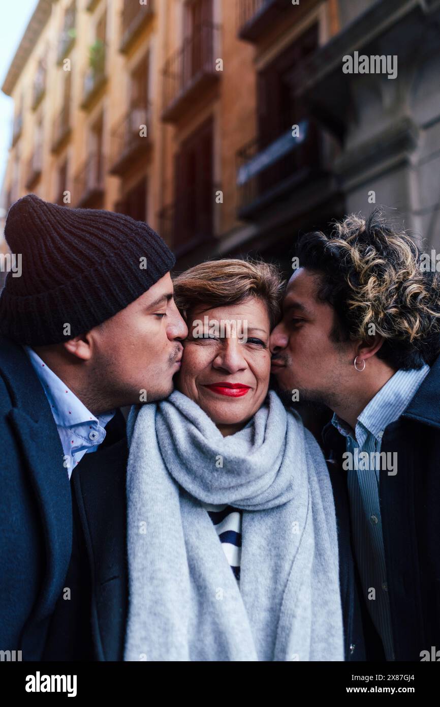 Uomini che baciano la madre di fronte all'edificio Foto Stock