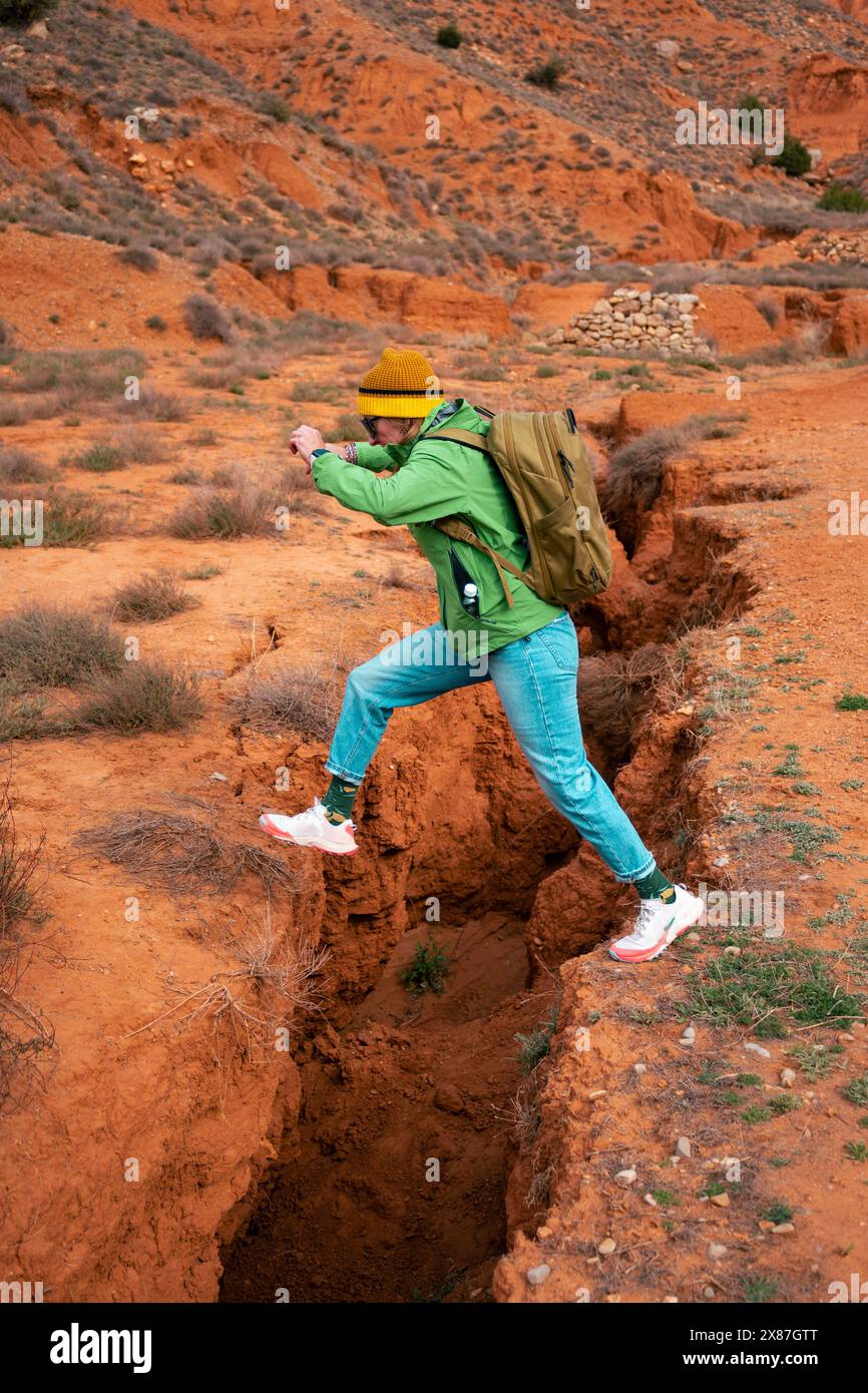 Donna matura che salta su un fossato nel canyon rosso Foto Stock