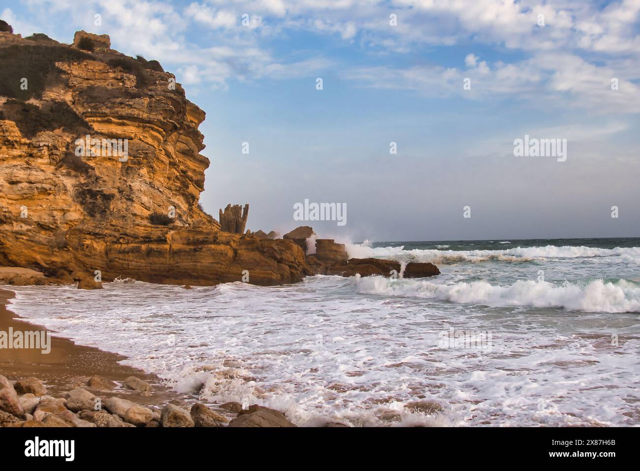 La spiaggia, le scogliere calcaree rosse, le onde schiaccianti e il mare tempestoso di Praia do Figueira, tra Sagres e Lagos, Algarve, Portogallo Foto Stock