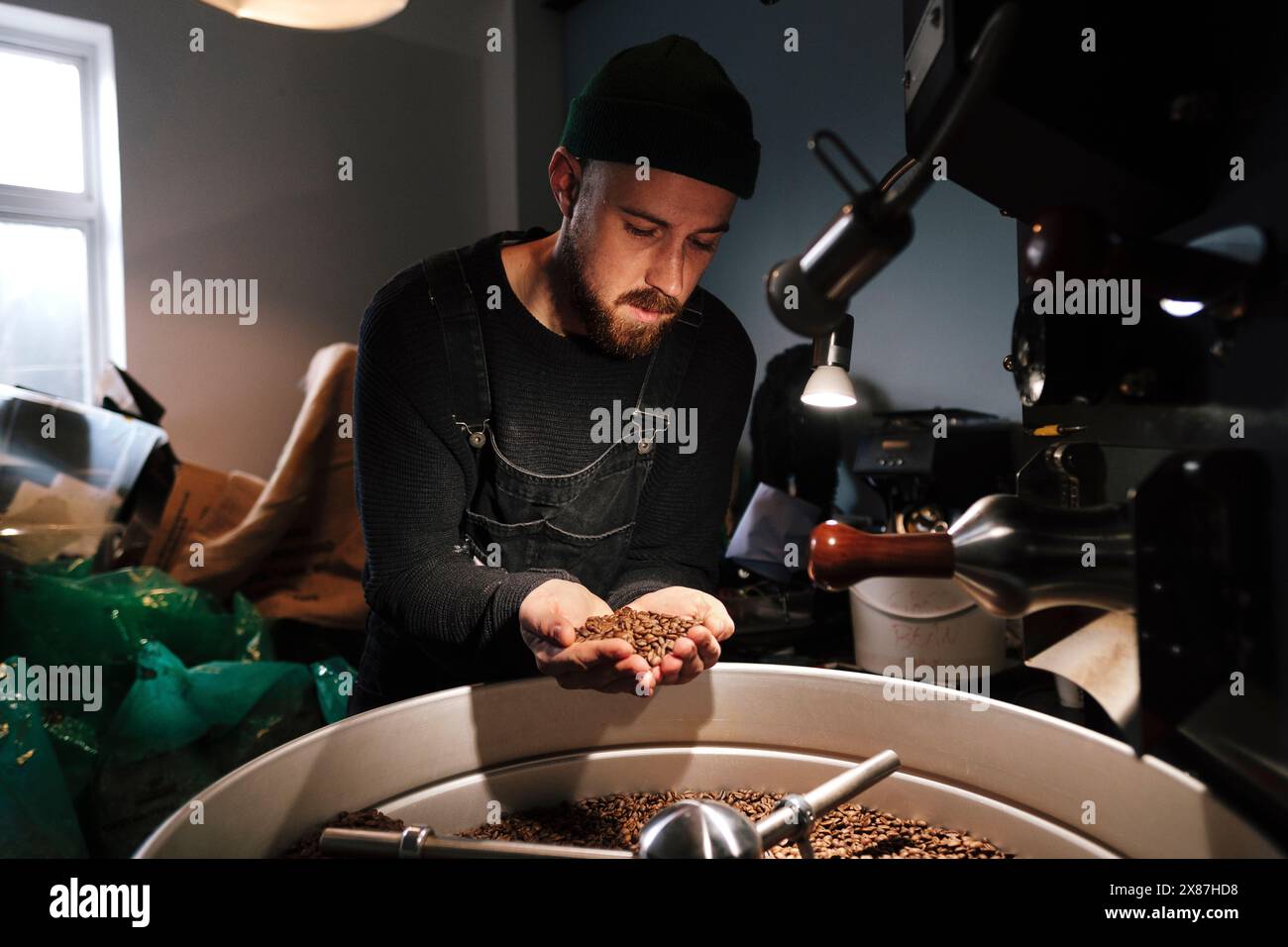 Torrefazione del caffè esaminando i chicchi di caffè tostati in prossimità di macchinari Foto Stock