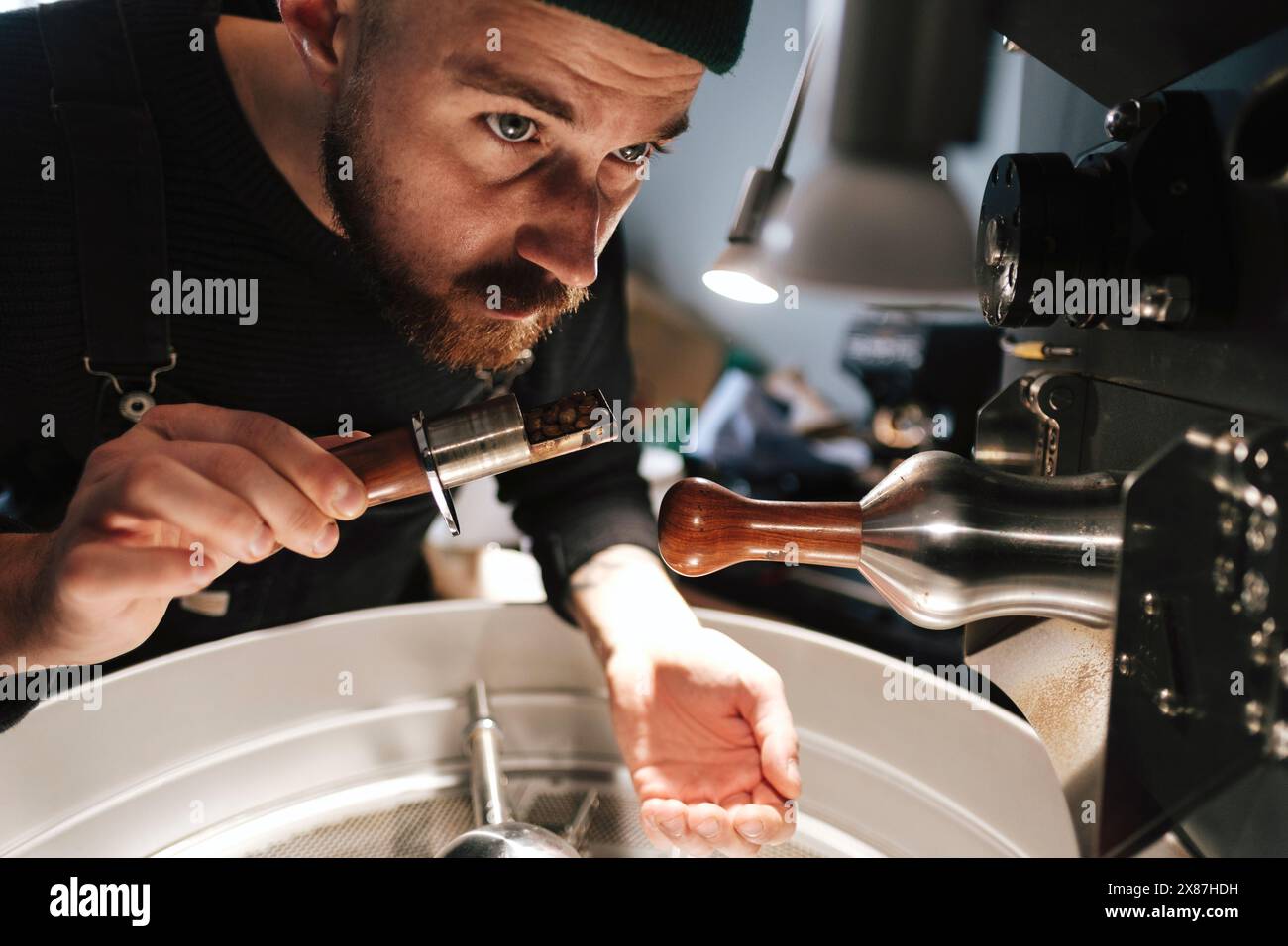 Coffee Roaster odora i chicchi ed esamina i macchinari in fabbrica Foto Stock