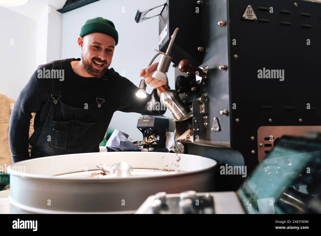 Happy Coffee Roaster che aziona macchinari in fabbrica Foto Stock