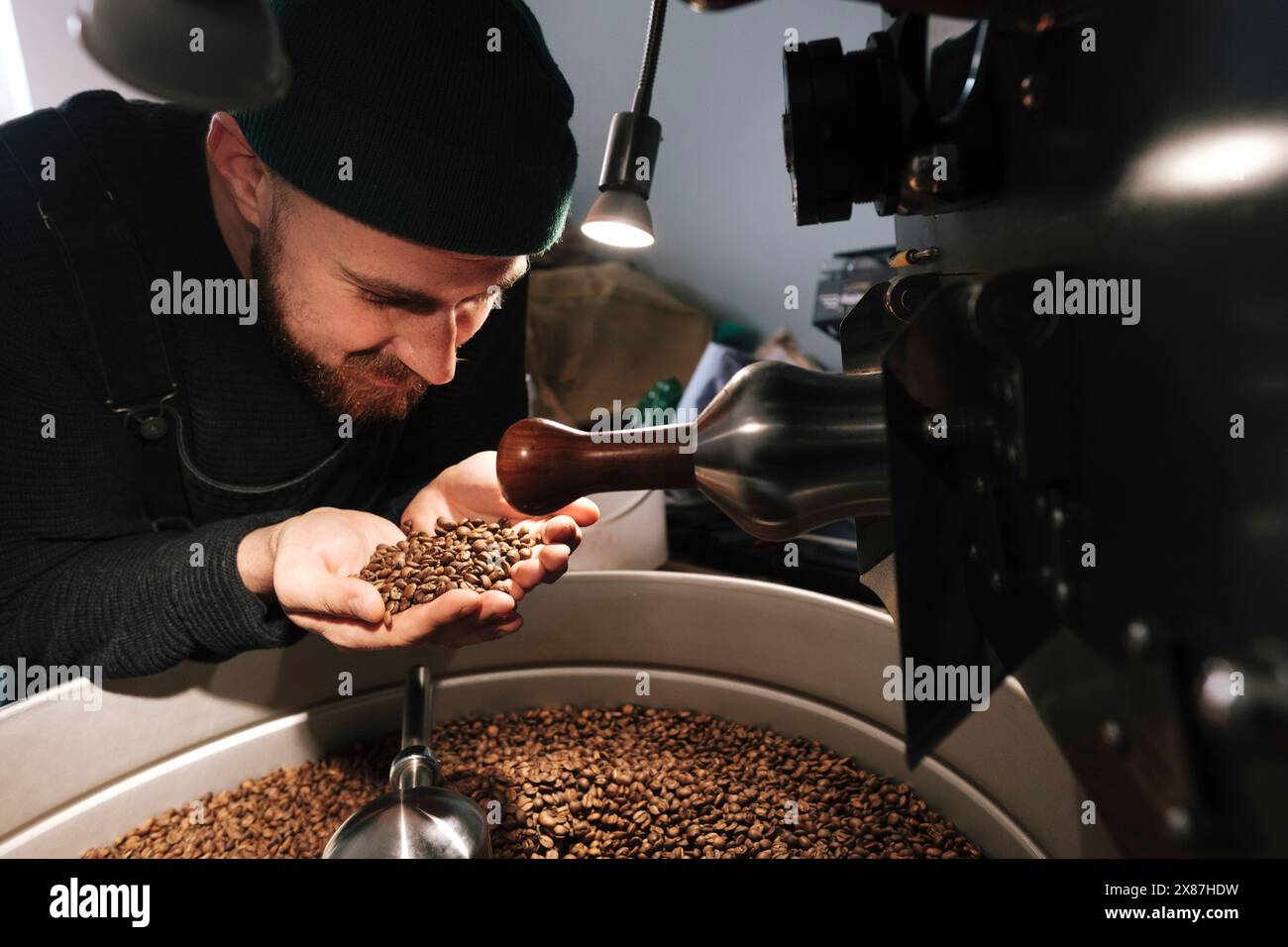 Torrefazione che tiene e puzza i chicchi di caffè vicino ai macchinari Foto Stock