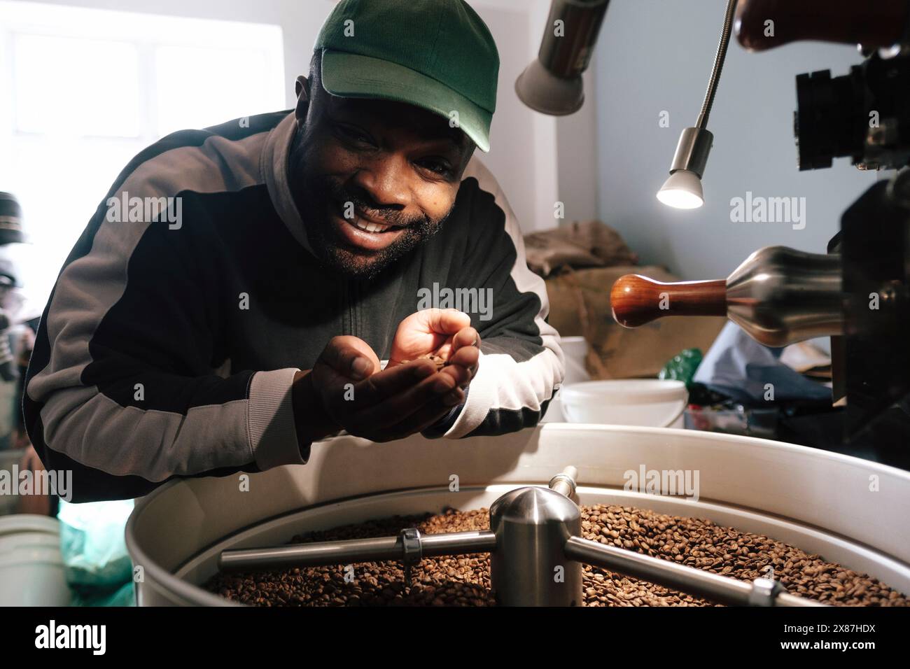 Torrefazione Happy Coffee che tiene i chicchi di caffè tostati vicino ai macchinari Foto Stock