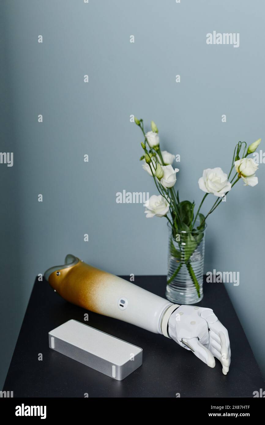 Braccio e vaso protesico con rose bianche sul comodino in camera da letto di casa Foto Stock