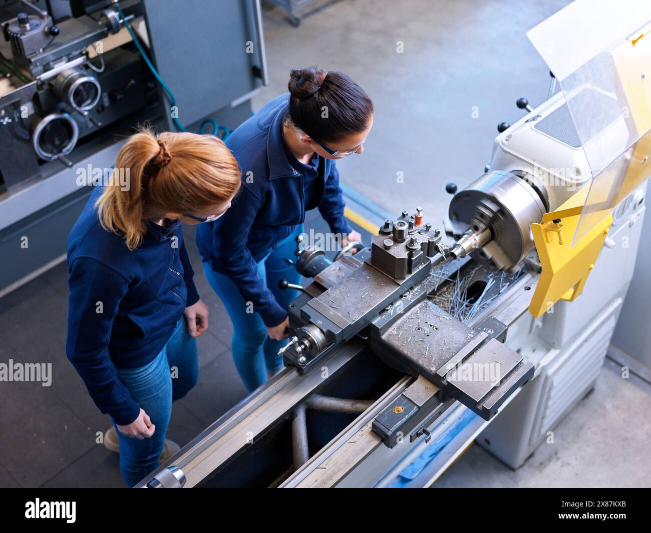 Istruttore che spiega i partecipanti al tornio nell'industria della lavorazione dei metalli Foto Stock