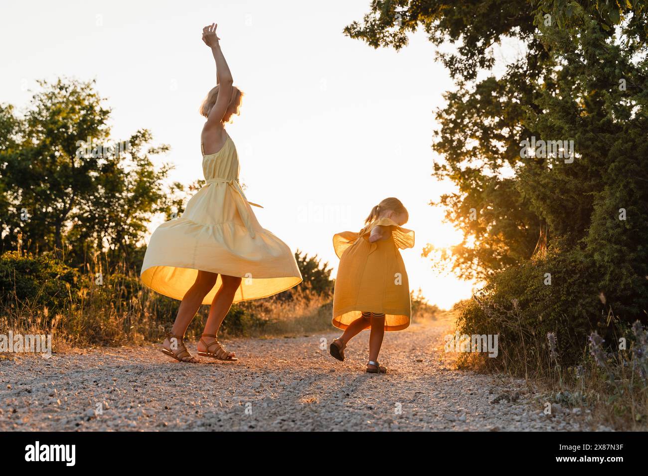 Madre e figlia ballano sul sentiero al tramonto Foto Stock