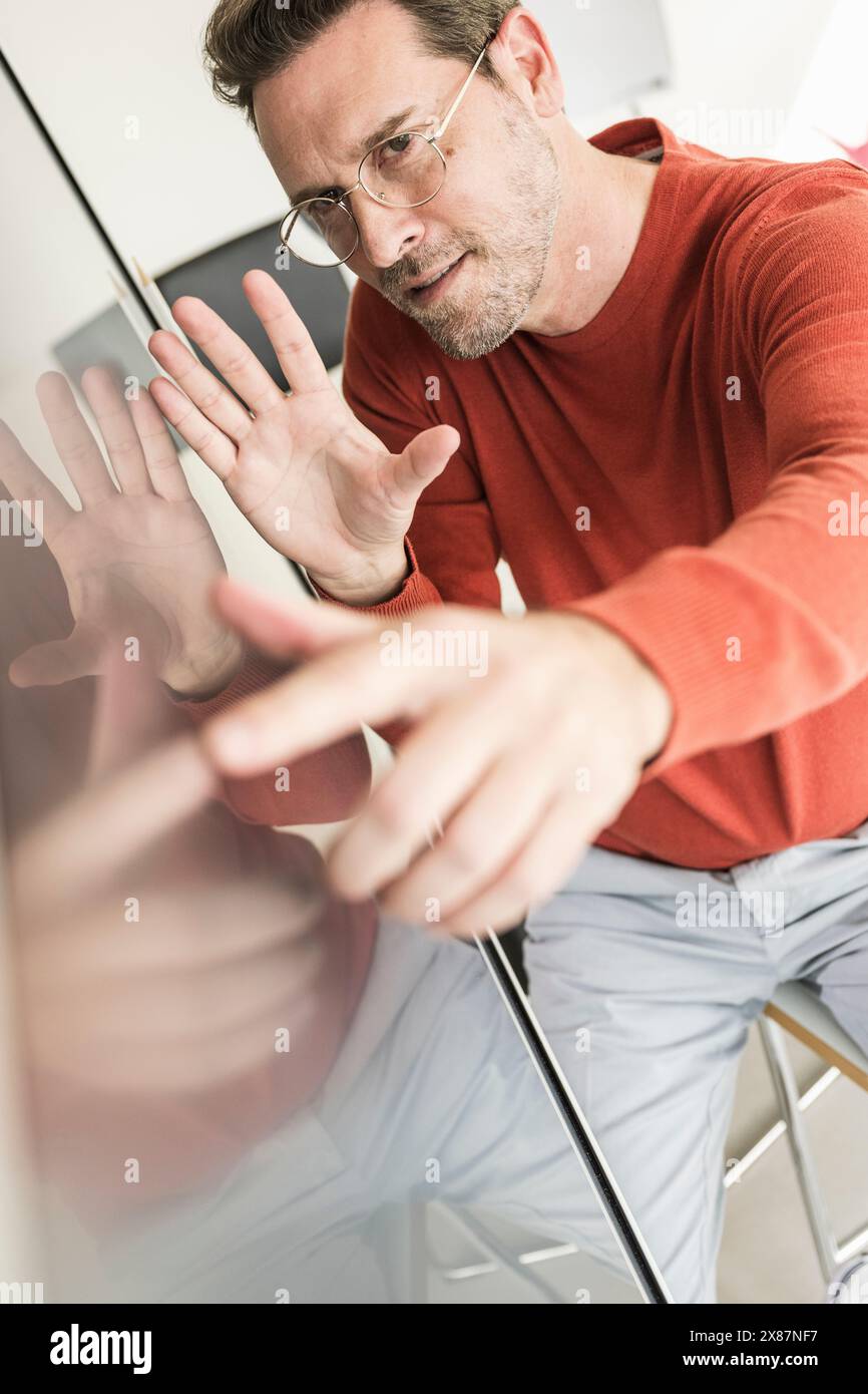 Uomo d'affari maturo e sicuro che tocca lo schermo in ufficio Foto Stock