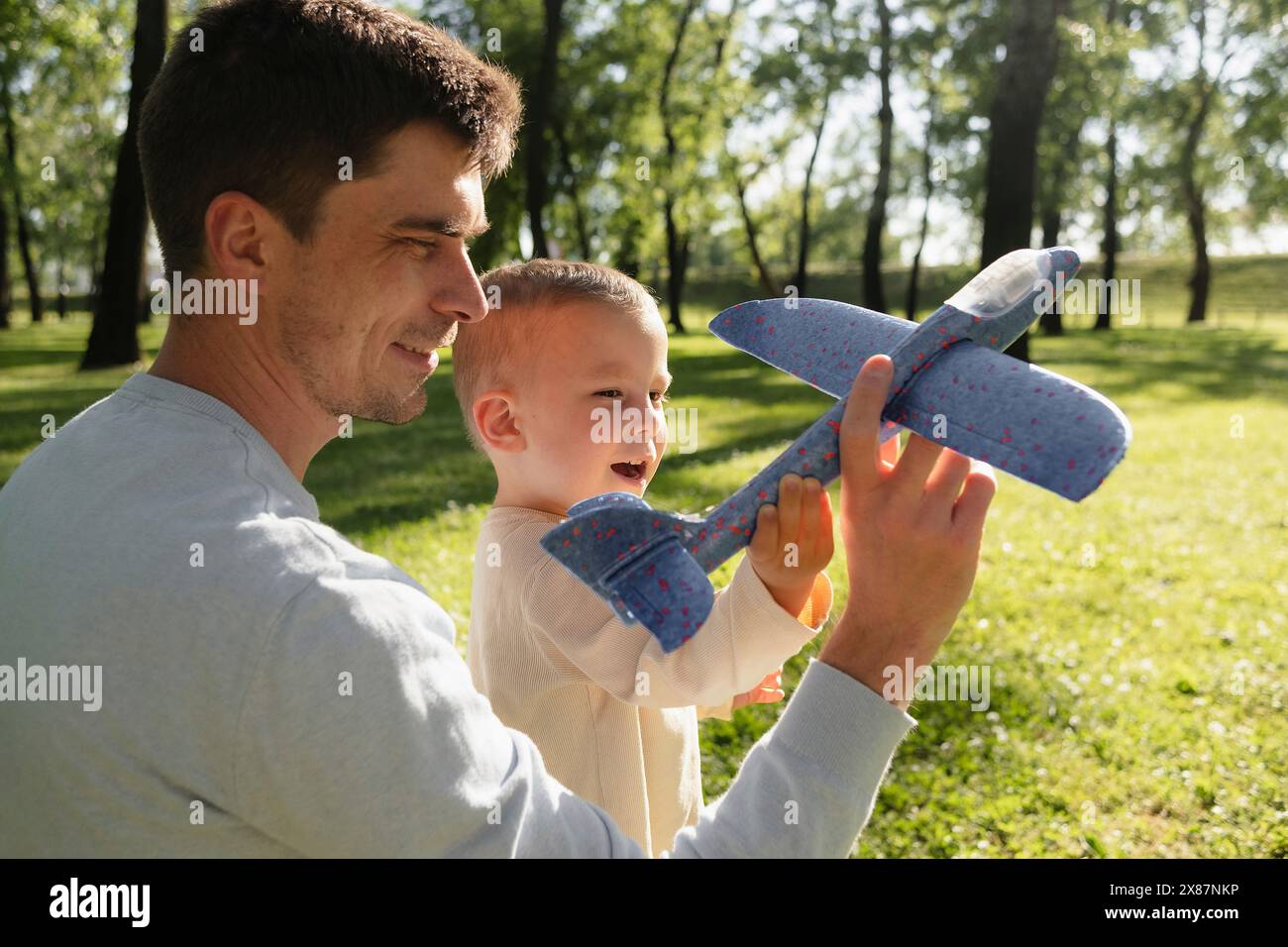 Padre e figlio giocano con l'aereo giocattolo al parco Foto Stock