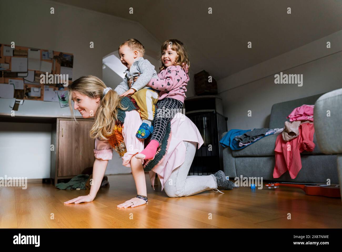Madre felice con bambini sul retro in salotto Foto Stock