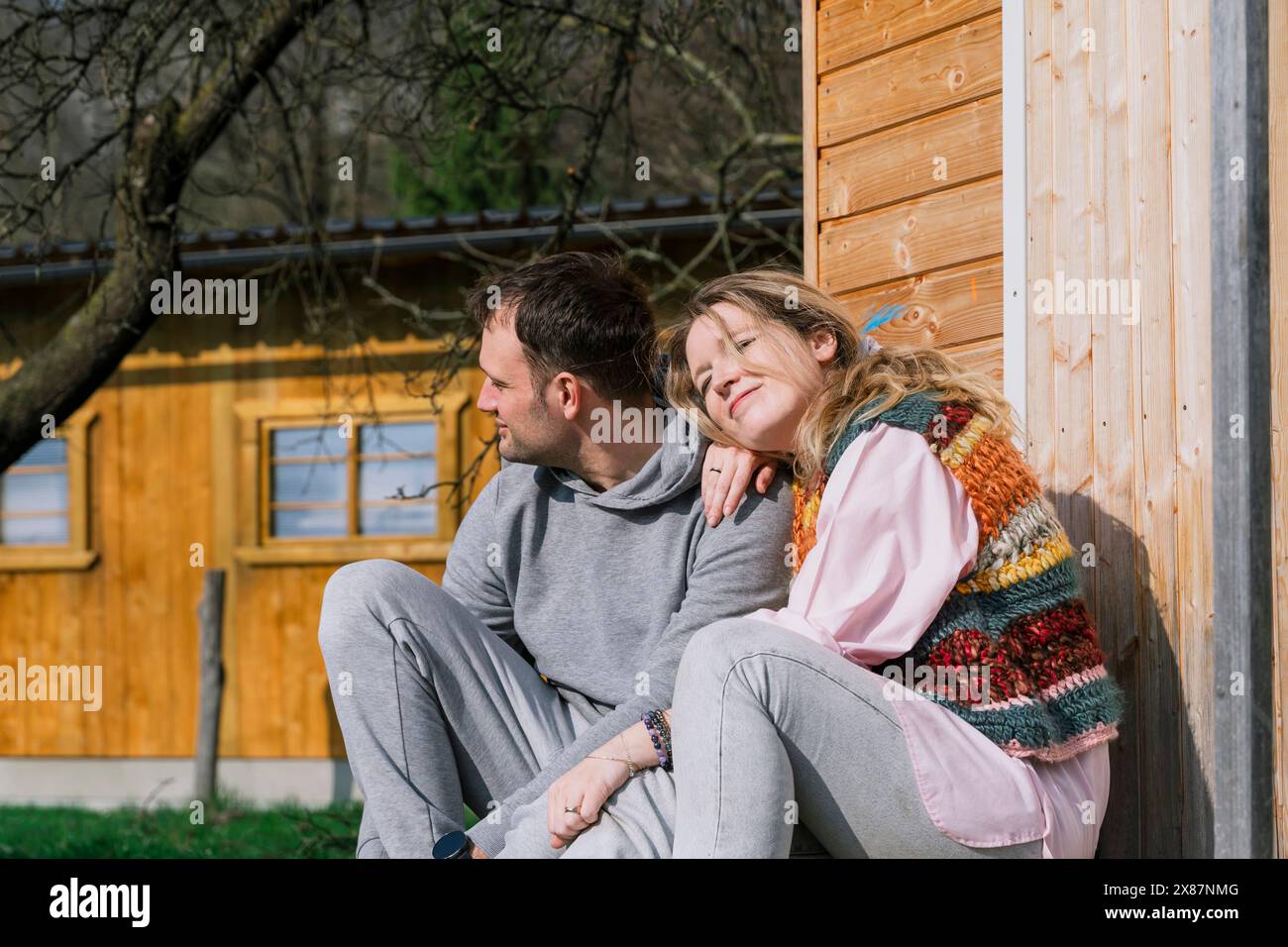 Coppia sorridente seduta insieme nel cortile posteriore nella giornata di sole Foto Stock