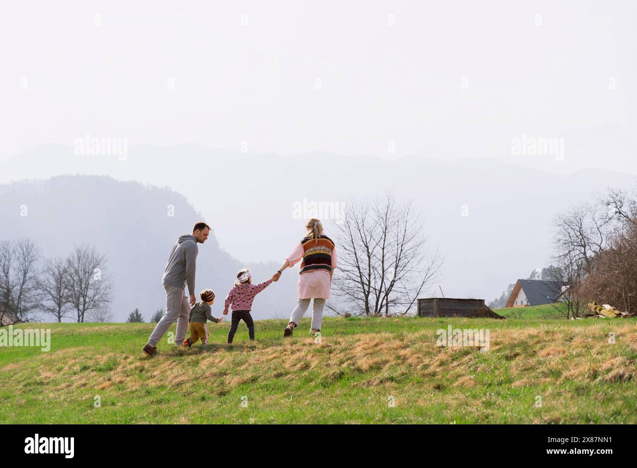 Genitori e bambini che camminano insieme sull'erba della fattoria Foto Stock