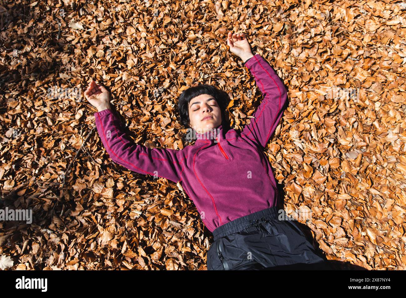 Donna spensierata sdraiata sulle foglie autunnali Foto Stock