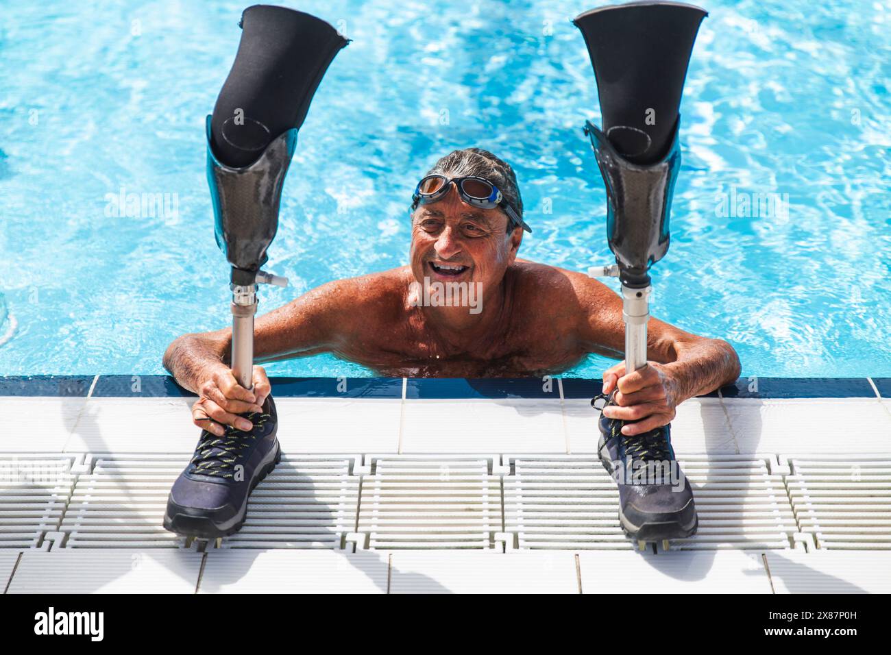 Uomo anziano felice senza camicia con gambe protesiche che nuotano in piscina nelle giornate di sole Foto Stock