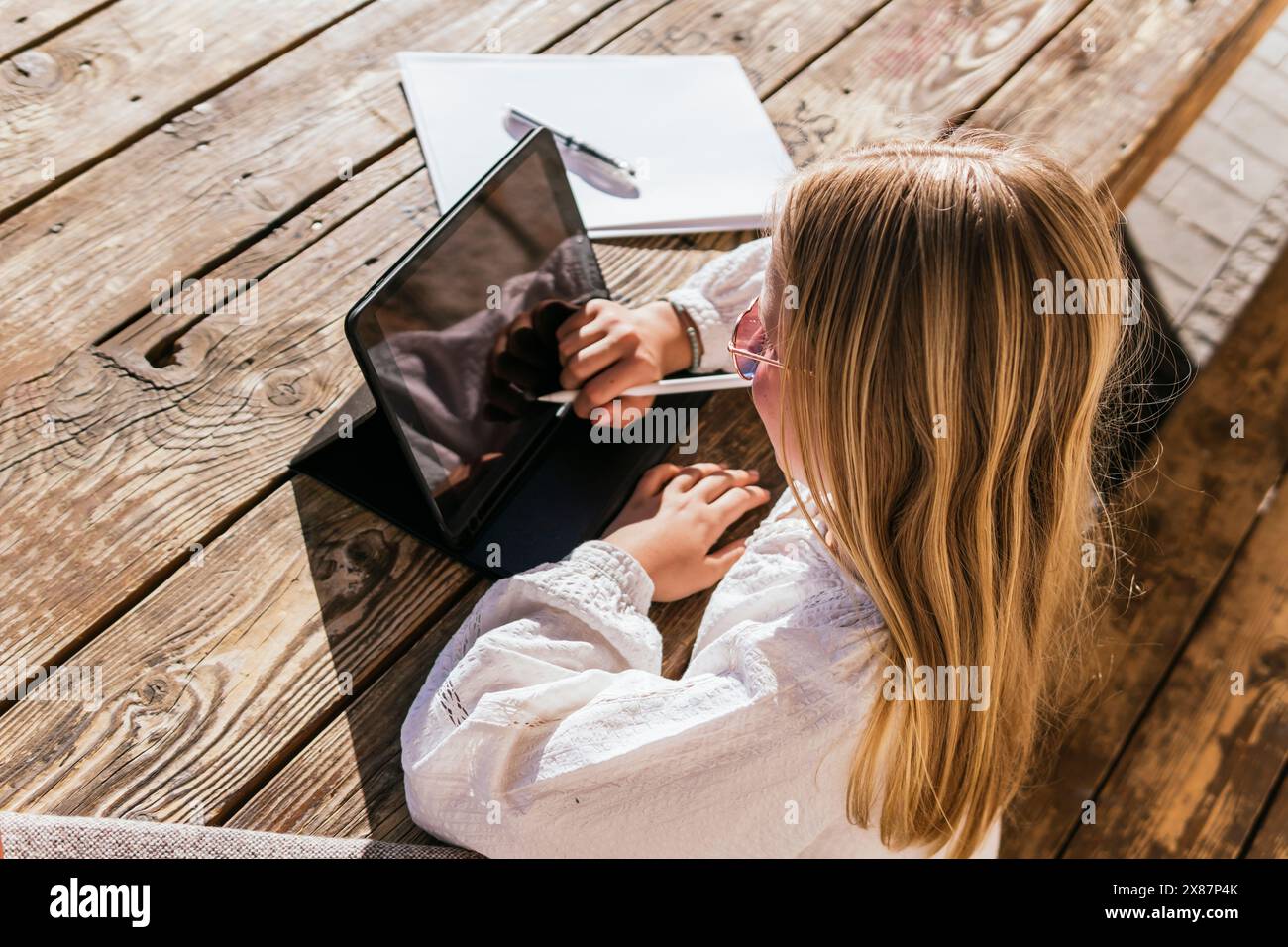 Ragazza che usa un tablet PC con una penna digitalizzata a tavola Foto Stock