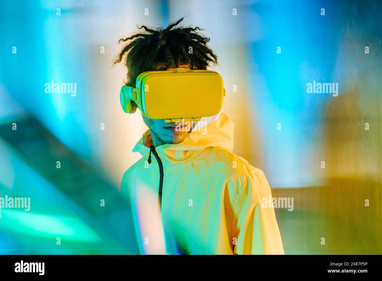 Uomo con giacca gialla che indossa un visore per realtà virtuale Foto Stock